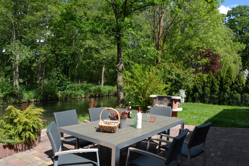 gedeckter Tisch auf der Terrasse am Wasser